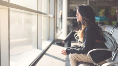 Woman looking out window at airport waiting for flight to board